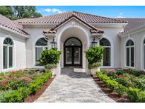 Elegant home exterior with arched entryway and manicured landscaping at 1306 Sweetwater Club Blvd, Longwood, FL 32779