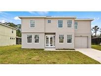 Two-story home featuring large windows, a well-maintained lawn, and a driveway leading to an attached garage at 4905 Pall Mall E St, Kissimmee, FL 34758