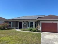 Charming one-story home featuring a well-maintained lawn, solar panels, and an attached red garage at 806 Grantham Dr, Kissimmee, FL 34758