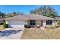 Single-story house with a white garage door and landscaped lawn at 4490 Treasure Cay Rd, Tavares, FL 32778