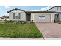 Charming one-story home with brick driveway, well-manicured lawn, and inviting curb appeal at 1390 Current Pl, Haines City, FL 33844