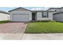 Charming one-story home with a well-manicured lawn, brick driveway, and gray trim at 1542 Mermaid Way, Haines City, FL 33844
