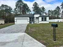 New construction home with gray and white exterior, paved driveway, and landscaped lawn at 6807 Sw 153Rd Place Rd # 6807, Ocala, FL 34473