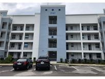 Modern condo building featuring balconies, blue accents, and ample parking for residents and guests at 3161 Paradox Cir # 202, Kissimmee, FL 34746