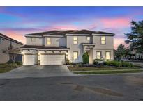 Elegant two-story home featuring a three-car garage and meticulously manicured landscaping at 7001 Oakwood St, Davenport, FL 33837