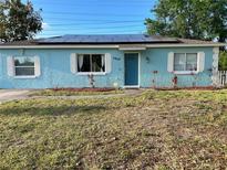 Charming single-story home with blue exterior, white trim, solar panels, and front yard at 3804 Janie Ct, Orlando, FL 32822