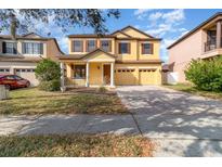 Two-story house with a yellow facade, brick driveway, and landscaping at 10064 Silver Laurel Way, Orlando, FL 32832