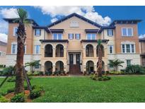 Beautiful Mediterranean style building with arched balconies, lush landscaping, and a vibrant green lawn at 2444 Lobelia Dr, Lake Mary, FL 32746