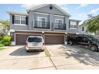 Two-story home with a gray exterior, brown garage doors, and a concrete driveway with a silver minivan and black truck at 6604 S Goldenrod Rd # 100B, Orlando, FL 32822