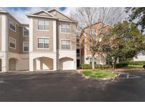 View of building exterior featuring garages, neutral color scheme, and well maintained landscaping at 12855 Madison Pointe Cir # 106, Orlando, FL 32821