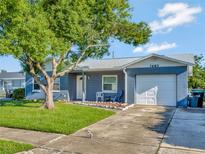 Blue house with a white garage door and a large tree in the front yard at 7685 Ceres Dr, Orlando, FL 32822