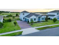 Beautiful two-story home with a manicured lawn and a brick driveway in a suburban neighborhood at 16744 Sanctuary Dr, Winter Garden, FL 34787