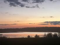 Scenic lake view at sunset with golden light reflecting off the water and silhouette of trees at 16744 Sanctuary Dr, Winter Garden, FL 34787