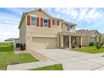 Inviting two-story home featuring red shutters, a two-car garage, screened in porch, and well-maintained landscaping at 205 Hamlet Rd, Davenport, FL 33837