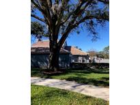 Quaint one-story home with a well-manicured lawn, beautiful tree, and a neutral color scheme at 4559 Oak Arbor Cir, Orlando, FL 32808