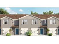 Charming townhomes boast a modern facade with blue doors, white garages, and neatly manicured landscaping at 559 Zinfandel Dr, Holly Hill, FL 32117
