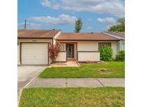 Charming single-story home featuring an attached garage, a well-maintained lawn, and beautiful, mature landscaping at 5875 Talavera St, Orlando, FL 32807