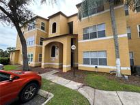 A view of the home's tan exterior with an arched entryway and colorful plants adding curb appeal at 4642 Commander Dr # 933, Orlando, FL 32822