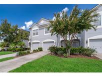 Two-story townhome with gray exterior, two-car garage, and landscaped yard at 15223 Windmill Harbor Ct, Orlando, FL 32828