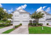 Two-story townhome with gray exterior, two-car garage, and landscaped yard at 15223 Windmill Harbor Ct, Orlando, FL 32828