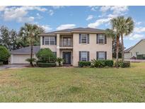 Two-story house with gray shutters, palm trees, and a well-manicured lawn at 105 James Pond Ct, Debary, FL 32713