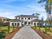 Two-story home with gray roof and paver driveway, offering curb appeal at 15023 Pendio Dr, Montverde, FL 34756