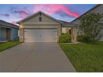 Tan house with white garage door and landscaping; sunset in background at 2321 Tay Wes Dr, Saint Cloud, FL 34771