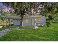 Light blue house with covered carport and a spacious lawn at 423 E 9Th St, Frostproof, FL 33843