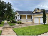 Charming single-story home with a welcoming porch, well-maintained lawn, and two-car garage at 9238 Kensington Row Ct, Orlando, FL 32827