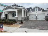 Two-story home with gray siding, stone accents, and a two-car garage at 16875 Muskgrass Dr, Winter Garden, FL 34787