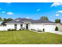 Charming single-story home with a well-manicured lawn, solar panels, and a two-car garage at 1302 Belmar Ter, Deltona, FL 32725