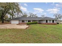 Charming single-story home featuring a brick facade, lush lawn, and a two-car garage at 6682 Sw 106Th Ln, Ocala, FL 34476