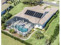 Stunning aerial view of home with pool, screened-in lanai, solar panels and lush landscaping at 5509 Meadow Hill Loop, Lady Lake, FL 32159