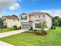 Two-story house with gray garage door, teal shutters, and landscaped lawn at 8060 Cherrystone St, Leesburg, FL 34748