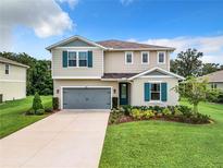 Charming two-story home featuring a gray garage door, blue shutters, and a well-maintained lawn and landscaping at 8060 Cherrystone St, Leesburg, FL 34748