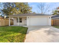 Newly constructed home with a white exterior, attached garage, and well-manicured lawn at 912 W 5Th St, Lakeland, FL 33805