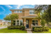 Two-story tan house with a blue door and landscaped yard at 16467 Olive Hill Dr, Winter Garden, FL 34787