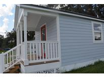 Newly built home with gray siding, white porch, and red door at 0 2Nd St, Oviedo, FL 32765