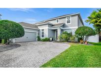 Charming two-story home with gray paint, paver driveway, manicured lawn and mature landscaping at 15558 Sandfield Loop, Winter Garden, FL 34787