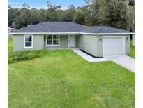 Newly constructed home with green exterior, landscaped lawn, and attached garage at Tbd Kilgore St, Wildwood, FL 34785