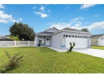 Cute one-story house with a white picket fence and a two-car garage at 805 Nelson Dr, Kissimmee, FL 34758