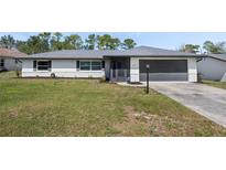 Charming single-story home with a well-manicured lawn and a gray two-car garage at 260 S Fairbairn Dr, Deltona, FL 32725