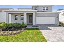 Contemporary home featuring a two-car garage, neutral tones, landscaped yard, and an inviting covered front entry at 1694 Pinecliff Dr, Apopka, FL 32703