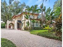 Elegant two-story home boasts a red tile roof, arched windows, porte cochere, and lush landscaping at 732 Edgewater Dr, Orlando, FL 32804