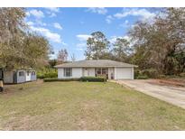 Charming single-story home featuring a brick facade, well-maintained lawn, and attached garage, plus an extra storage building at 35600 Harbor Shores Rd, Leesburg, FL 34788