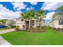 Charming single-story home with a well-manicured lawn and beautiful landscaping featuring palm trees at 886 Grazie Loop, Davenport, FL 33837
