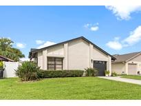 Updated single-story home with a landscaped lawn and a modern garage door at 2874 Autumn Green Dr, Orlando, FL 32822