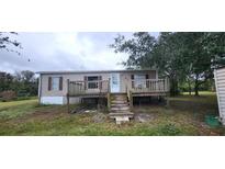 Tan single-wide mobile home with wooden deck and steps at 2661 Waccassa St, Geneva, FL 32732