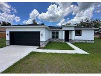 Charming single-story home with a black garage door, white stucco and well-manicured lawn at 442 Marion Oaks Crse, Ocala, FL 34473