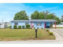 Charming single-story home featuring a light blue exterior, red accents, a covered carport, and a well-manicured front lawn at 926 Everett St, Lake Alfred, FL 33850